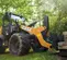 Orange and black Case wheel loader lifting a pallet of cement blocks in a wooded area