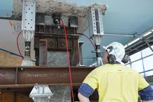 Safety specialist inspecting a hydraulic jacking system at a construction site to ensure proper setup and operation.
